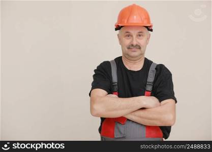 Construction worker in overalls and hard hat. Repairman with a mustache worker crossed his arms over his chest. Business, technology. Building concept. Studio shot on white background.. Construction worker in overalls and hard hat. Repairman with a mustache worker crossed his arms over his chest. Business, technology. Building concept. Studio shot on white background