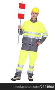 construction worker in safety outfit holding construction sign