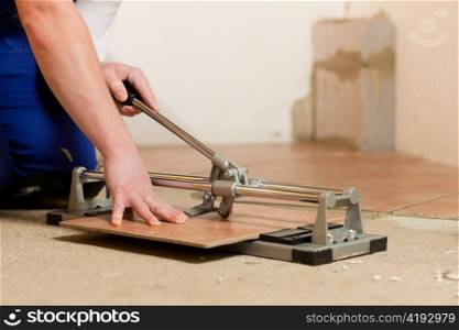 Construction worker is cutting tiles at home