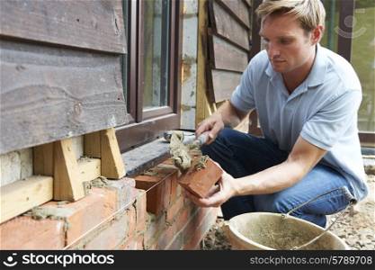 Construction Worker Laying Bricks On Site