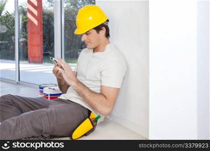 Construction worker looking in cellphone while sitting