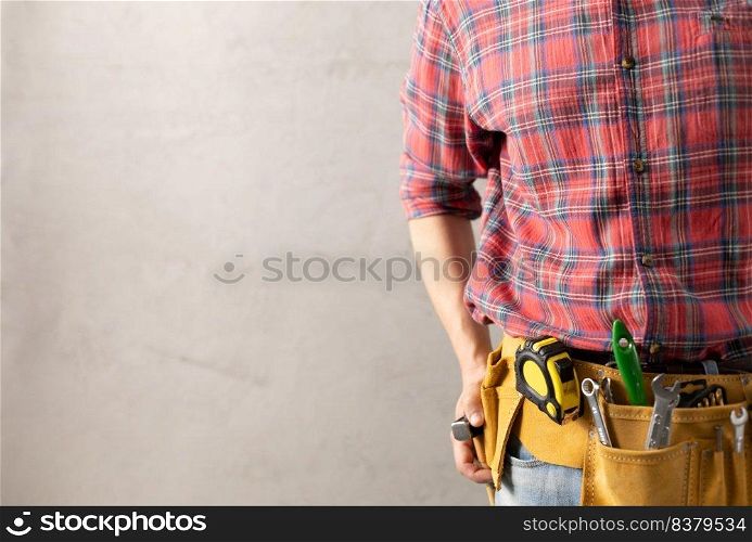Construction worker man and tool belt in house room renovation. Male hand and construction tools near concrete wall. Home renovation concept