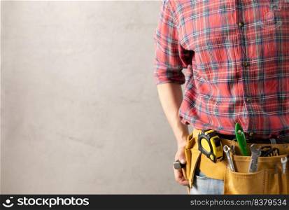 Construction worker man and tool belt in house room renovation. Male hand and construction tools near concrete wall. Home renovation concept