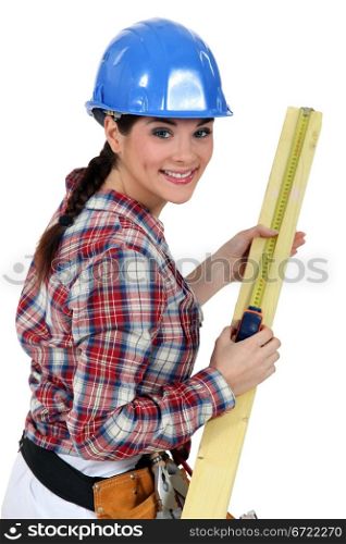 Construction worker measuring a piece of wood