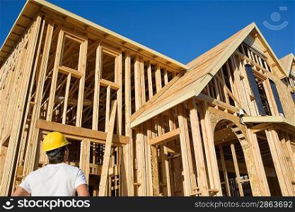 Construction worker observing unfinished house