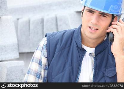 Construction worker on a call next to a pile of curbing