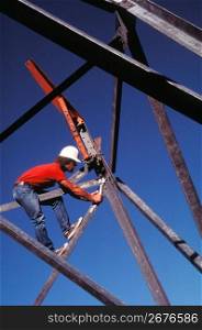 Construction worker on construction site balanced on girder using wrench to tighten metal supports