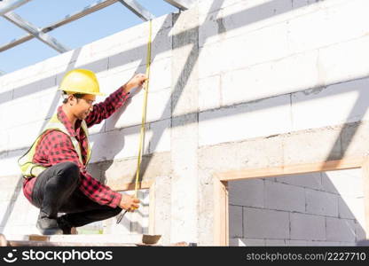 Construction worker or contractor man using measuring tape checking from steel  roof frame to the door on building construction site, foreman taking measurements wall while working