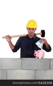 Construction worker putting money into a piggy bank