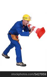 Construction worker shouting into a traffic cone
