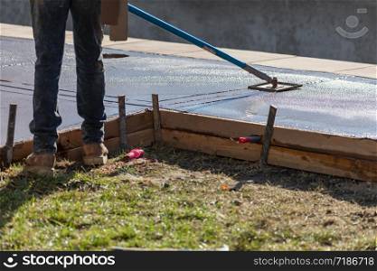 Construction Worker Smoothing Wet Cement With Long Handled Edger Tool