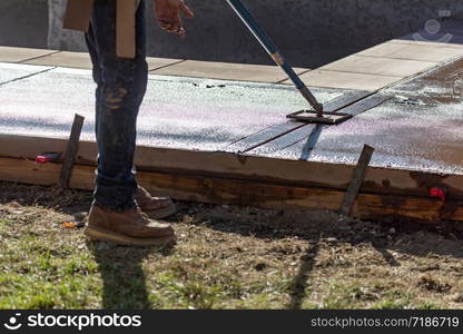 Construction Worker Smoothing Wet Cement With Long Handled Edger Tool