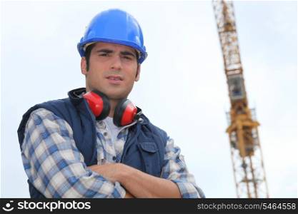 Construction worker standing in front of a crane