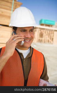 Construction worker standing on construction site and talking in mobile phone