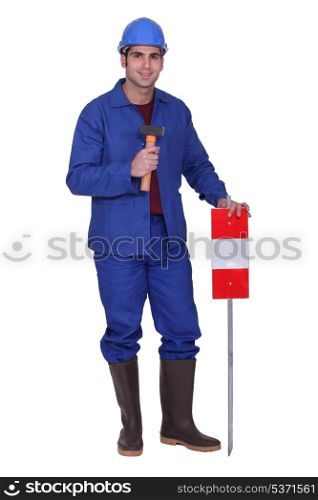 Construction worker standing with a mallet and traffic sign