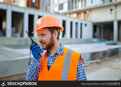 Construction worker using walkie-talkie for wireless communication. Building site area. Builder worker using walkie-talkie on construction site