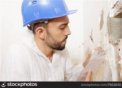 construction worker wearing helmet taking notes on clipboard
