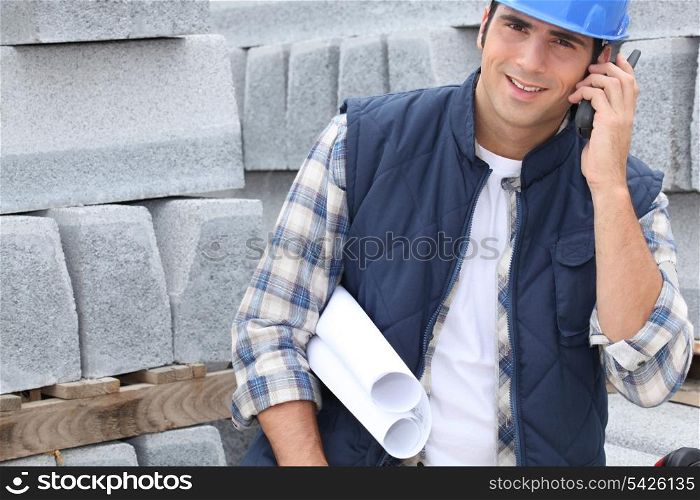 Construction worker with building plans and cellphone