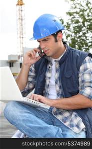 Construction worker with computer and phone
