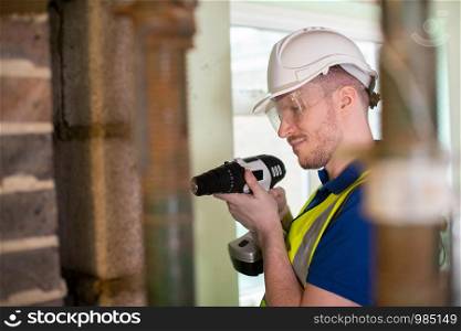 Construction Worker With Cordless Drill Drilling Wall In Renovated House