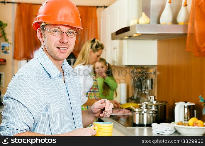 Construction worker with hardhat and father of a family having a morning cup of coffee before heading for his workplace