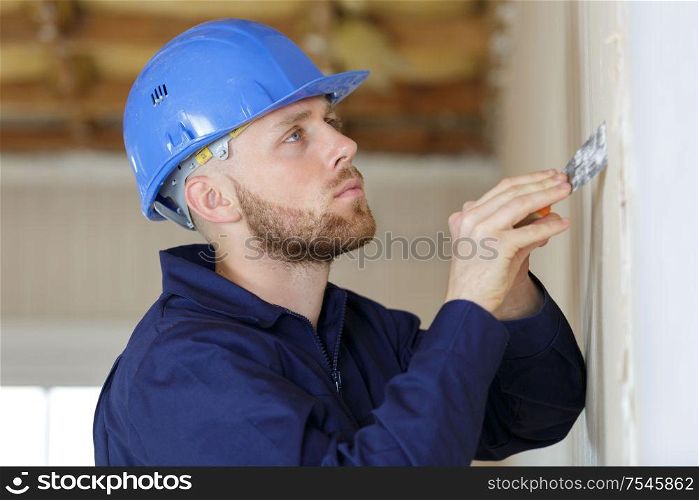 construction worker with long trowel plastering a wall