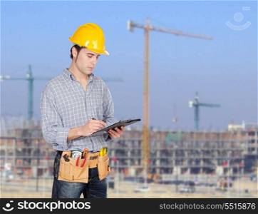 Construction worker writing paperwork with a construction building of background