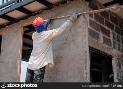 Construction workers plastering building wall using cement plaster