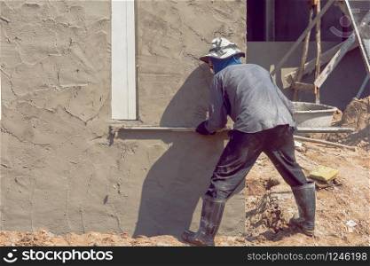 Construction workers plastering building wall using cement plaster
