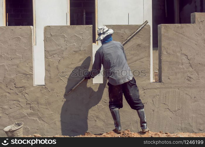 Construction workers plastering building wall using cement plaster