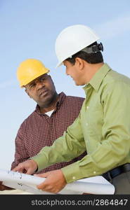 Construction workers studying blueprints outdoors