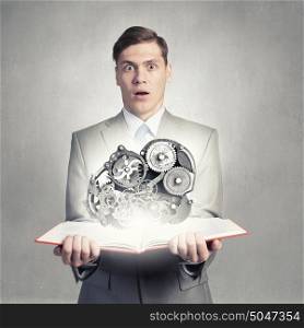 Constructive thinking. Businessman holding book and gears flying out of pages