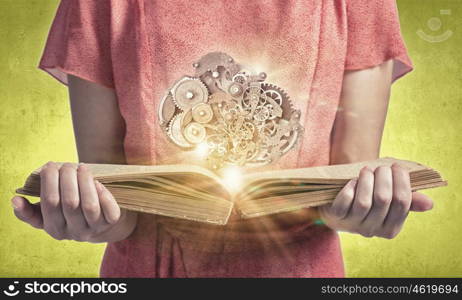 Constructive thinking. Young woman in red dress with book in hands and gears mechanism in air