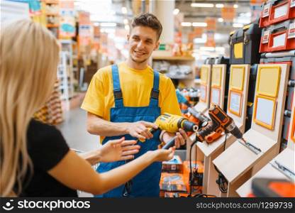 Consultant and female consumer in hardware store. Seller in uniform and woman in diy shop, shopping in building supermarket