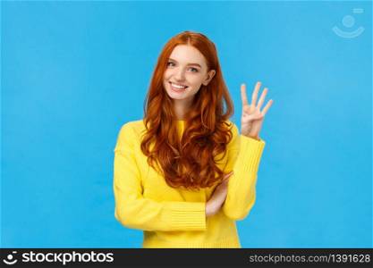 Consumer, shopping and fashion concept. Attractive ginger girl, redhead woman making reservetion, place order four products, smiling and gazing friendly camera, counting with fingers, blue background.. Consumer, shopping and fashion concept. Attractive ginger girl, redhead woman making reservetion, place order four products, smiling and gazing friendly camera, counting with fingers, blue background
