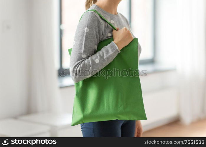 consumerism and eco friendly concept - woman with green reusable canvas bag for food shopping on grey background. woman with reusable canvas bag for food shopping