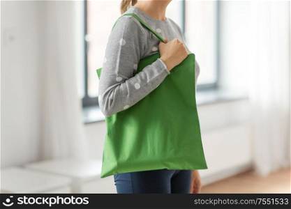 consumerism and eco friendly concept - woman with green reusable canvas bag for food shopping on grey background. woman with reusable canvas bag for food shopping