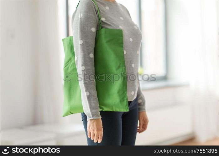 consumerism and eco friendly concept - woman with green reusable canvas bag for food shopping on grey background. woman with reusable canvas bag for food shopping