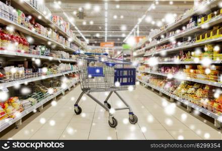 consumerism concept - empty shopping cart or trolley at supermarket over snow. empty shopping cart or trolley at supermarket