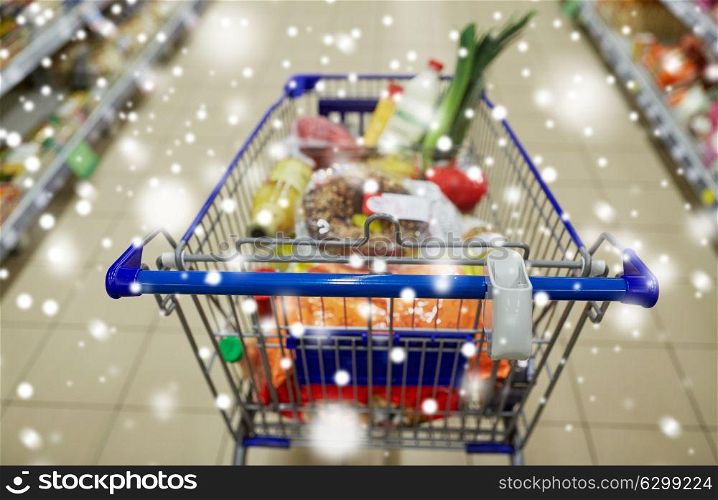 consumerism concept - food in shopping cart or trolley at supermarket over snow. food in shopping cart or trolley at supermarket