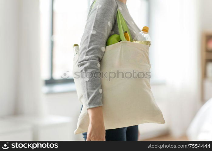 consumerism, eating and eco friendly concept - woman with white reusable canvas bag for food shopping on grey background. woman with reusable canvas bag for food shopping