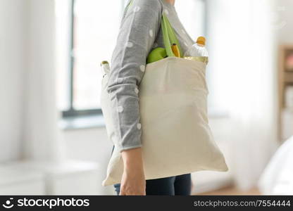 consumerism, eating and eco friendly concept - woman with white reusable canvas bag for food shopping on grey background. woman with reusable canvas bag for food shopping