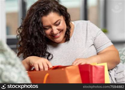 consumerism, people and sale concept - happy smiling young woman with shopping bags at home. happy young woman with shopping bags at home