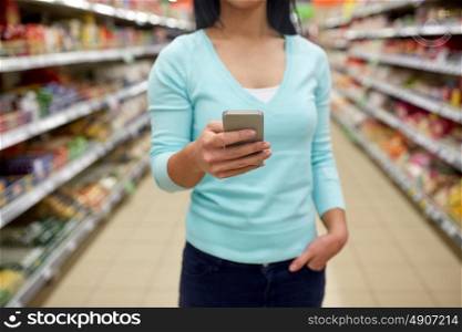 consumerism, shopping, technology and people concept - close up of woman with smartphone at shop or supermarket. woman with smartphone at shop or supermarket