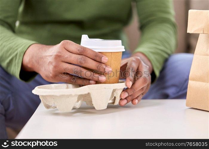 consumption and people concept - close up of man with takeaway coffee and food at home. close up of man with takeaway coffee and food