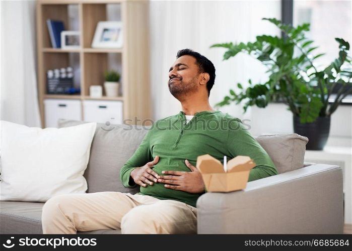 consumption and people concept - full and pleased indian man eating takeaway food at home. pleased indian man eating takeaway food at home