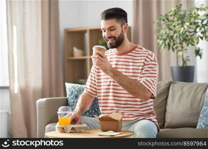 consumption, delivery and people concept - smiling man with takeaway food and drinks at home. smiling man with takeaway food and drinks at home