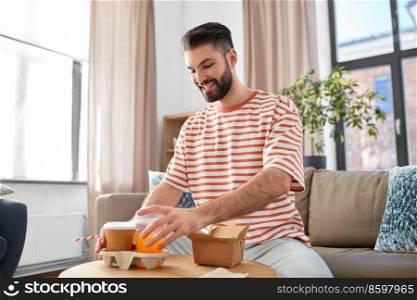 consumption, delivery and people concept - smiling man with takeaway food and drinks at home. smiling man with takeaway food and drinks at home