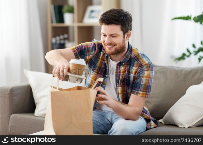 consumption, eating and people concept - smiling man unpacking takeaway food at home. smiling man unpacking takeaway food at home