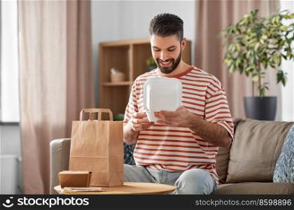 consumption, eating and people concept - smiling man unpacking takeaway food in paper bag at home. smiling man unpacking takeaway food at home